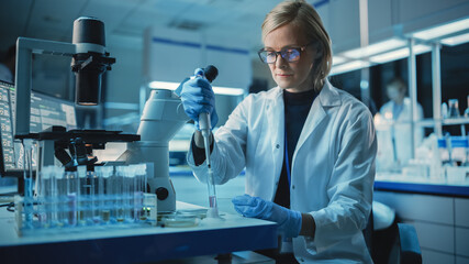 Female Research Scientist is Wearing Glasses and Using Micropipette to Extract a Sample on a...