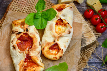 Home made italian  mini calzone  salami pizza with  tomatoes, mozzarella and parmesan cheese and fresh basil 