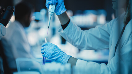 Close Up of a Research Scientist Using Micropipette to Mix Liquids in a Test Tube in a Modern...