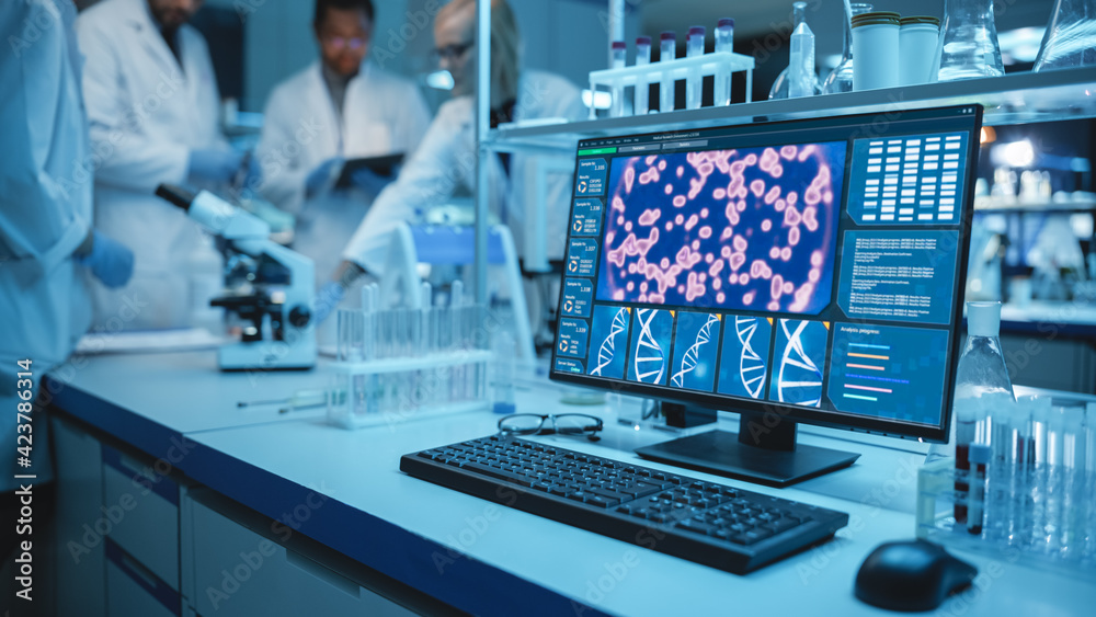 Wall mural shot of a desktop computer with display showing gene editing interface. diverse team of medical rese