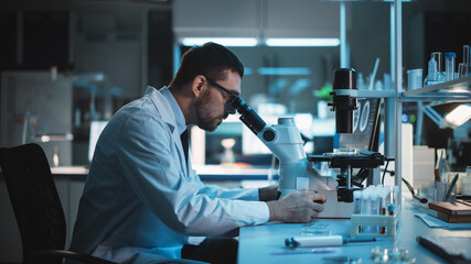 Medical Development Laboratory: Caucasian Female Scientist Looking Under Microscope, Analyzes Petri...