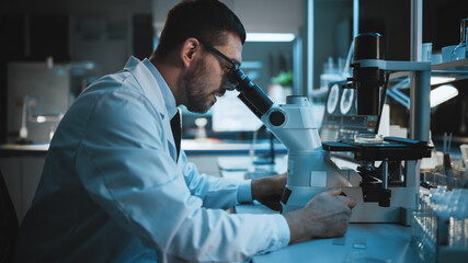 Medical Development Laboratory: Caucasian Female Scientist Looking Under Microscope, Analyzes Petri Dish Sample. Specialists Working on Medicine, Biotechnology Research in Advanced Laboratory