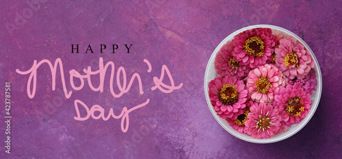Happy Mother's day banner with top view of zinnia floral background on purple texture.
