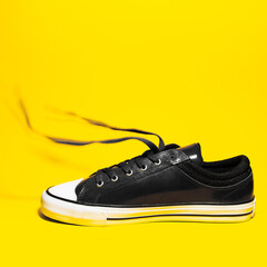 Close-up of vintage sneaker shoe with lace out on yellow background.