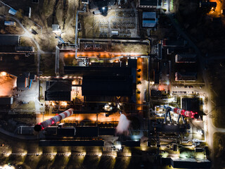 Aerial shot of industrial area at night with chimneys of thermal power plant station with smoke in Vilnius