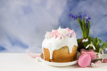 Easter background-easter cake with merinques , easter egg and spring flowers, blue background. Template for greeting card