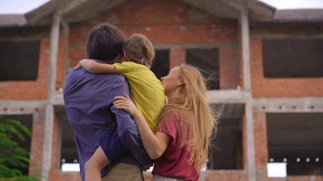 A family father, mother, and son look at their house that is under construction. They are imagining how they will live happily in this house