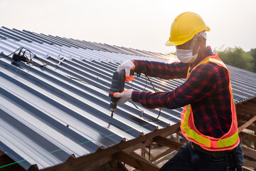Construction worker safety wear using electric drill tools install on new roof metal sheet, Roof...