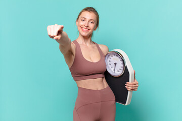 young pretty sport woman pointing or showing and holding a weight scale