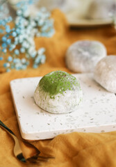 A traditional Japanses fresh homemade rice mochi bun with green tea matcha filling top with matcha powder blur background 