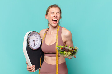 young pretty sport woman angry expression and holding a scale and a salad