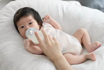 Obraz na płótnie Canvas Newborn baby holding mother's hand on a white bed.