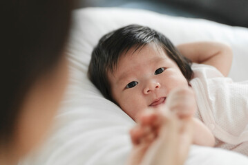 Fototapeta na wymiar Newborn baby holding mother's hand on a white bed.