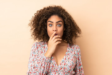Fototapeta na wymiar Young African American woman isolated on beige background surprised and shocked while looking right