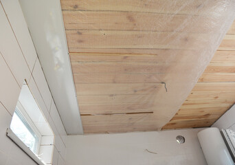 Bathroom renovation: Installing PVC ceiling cladding, plastic ceiling panels over a vapor barrier...