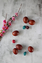 Beautiful branches with bright pink flowers and decorative Easter eggs on a cement background. Easter concept. Top view.