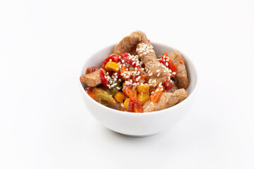 Meat with vegetables and sesame seeds on gray background with yellow cloth