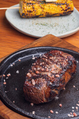 Grilled steak and garnish yellow corn on wooden table. Mexican gourmet food.