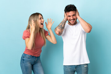 Young caucasian couple isolated on blue background frustrated and shouting
