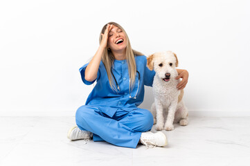 Young veterinarian woman with dog sitting on the floor smiling a lot