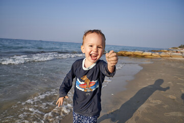 Fototapeta na wymiar Kind spielt am Strand am Meer mit Sand