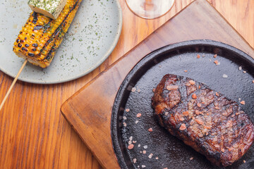Grilled steak and garnish yellow corn on wooden table. Mexican gourmet food.