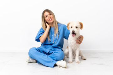 Young veterinarian woman with dog sitting on the floor laughing