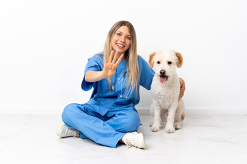 Young veterinarian woman with dog sitting on the floor happy and counting four with fingers