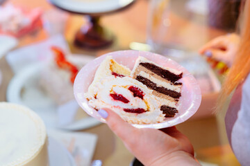 Tasting of sliced ​​pieces of cake. A slice of thin guest cake on a recyclable cardboard plate.