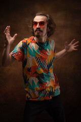 A young man poses in red glasses and a bright T-shirt. Surprise, dance, fooling, prank. A man with a sense of humor.