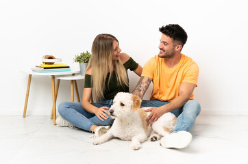 Young caucasian couple with dog staying at home happy and smiling