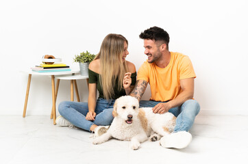 Young caucasian couple with dog staying at home smiling a lot