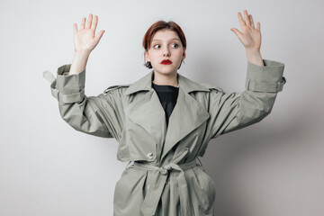 The young woman raised her hands, surrenders. White wall background