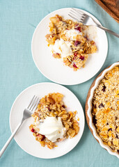 Apple and pear crumble with ice cream, streusel. Sweet dessert with stewed fruit topped crisp crumbly mixture served ice cream. Two plate with apple cobbler. Top view, vertical