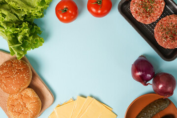 Homemade burger ingredients on blue table background with copy space