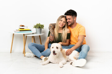 Young caucasian couple with dog staying at home hugging
