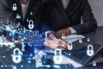 Two businesswomen working on the project to protect cyber security of international company. Padlock Hologram icons over the table with documents.