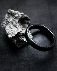 men leather bracelet and an stone on black background