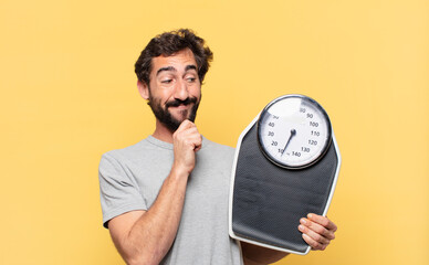 young crazy bearded man dieting thinking expression and holding a weight scale