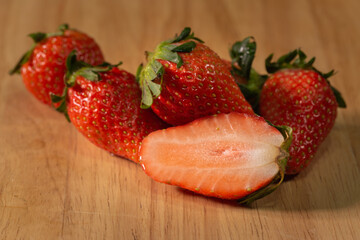 the sweet soft red fruit with a seed-studded surface cut in half on the wood.