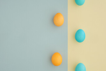 Creative Easter background with yellow and blue eggs on a two-color pastel background with space for text, top view, flat lay. Postcard, congratulations, minimalism, aesthetics
