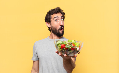 young crazy bearded man dieting surprised expression and holding a salad