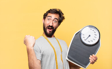 young crazy bearded man dieting celebrating successful a victory and holding a sweight scale