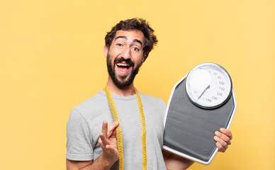 young crazy bearded man dieting happy expression and holding a sweight scale