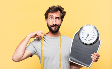 young crazy bearded man dieting scared expression and holding a sweight scale