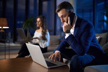 Man and woman working on laptops at home