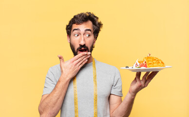 young crazy bearded man dieting scared expression and holding waffles