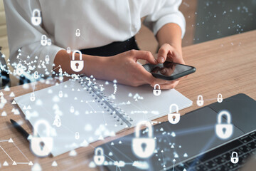 A woman programmer is browsing the Internet in smart phone to protect a cyber security from hacker attacks and save clients confidential data. Padlock Hologram icons over the typing hands. Formal wear