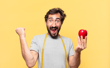 young crazy bearded man dieting celebrating successful a victory and holding an apple