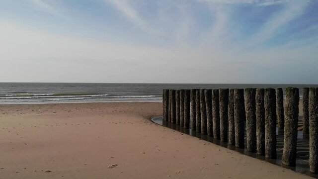 Scenic View Of Sandy Beach With Old Wood Pilings Near The Shore In Brouwersdam, Netherlands - wide shot